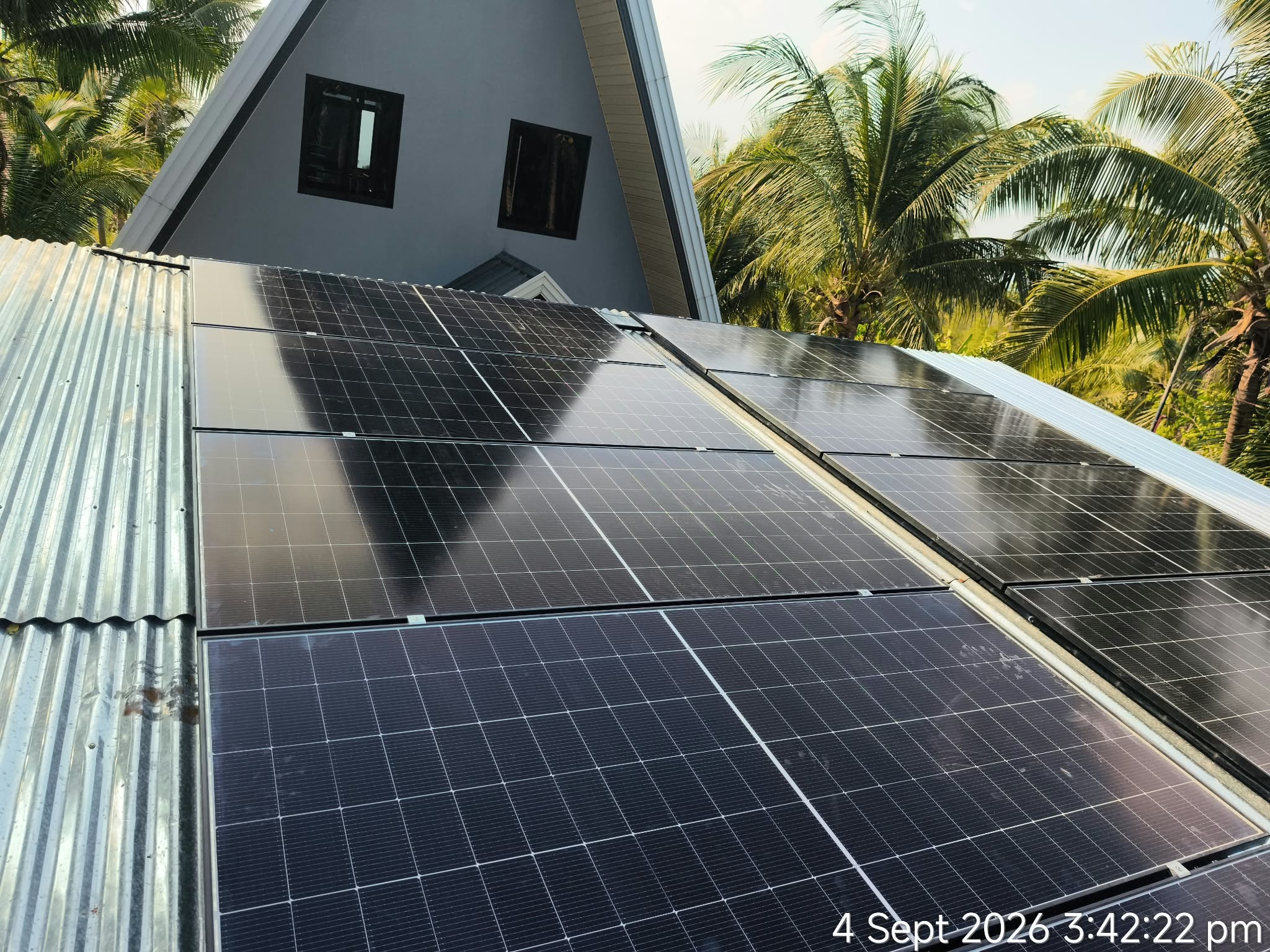 Solar panels installed on a home roof in a tropical setting.