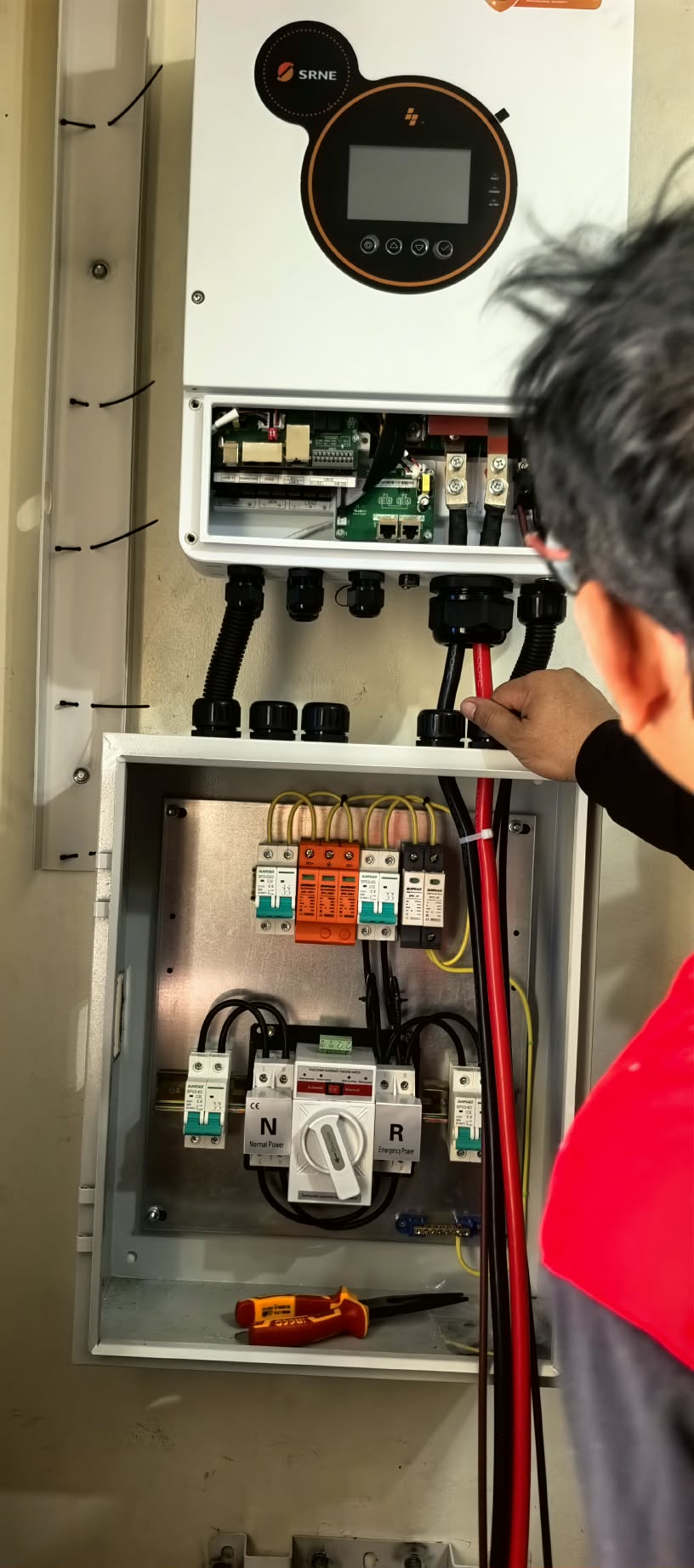 Installer checking an open electrical panel during solar system work.